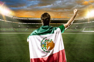 hombre alentando a la seleccion mexicana en estadio de futbol con la bandera en su espalda bandera de mexico soccer estadio .jpg